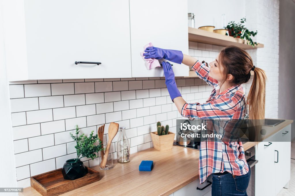 Woman in gloves cleaning cabinet with rag at home kitchen. Woman in gloves cleaning cabinet with rag at home kitchen Kitchen Stock Photo