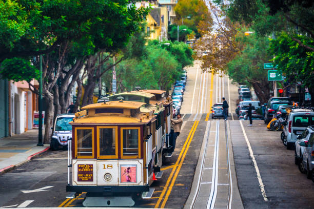 San Francisco Cable Car San Francisco, USA - November 4, 2017: Vintage cable car running up the steep street in San Francisco.  Invented in San Francisco near 150 years ago, cable cars have no engine or motor on themselves. They are pulled along by cables running beneath the street. trolley bus stock pictures, royalty-free photos & images