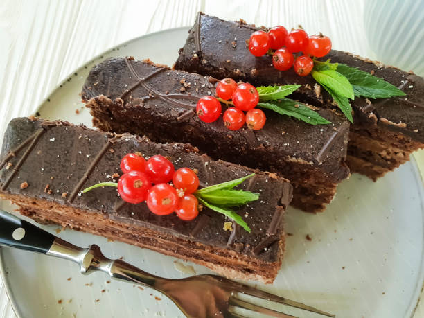 istock chocolate cake, red currant, mint plate on white wooden 972839304