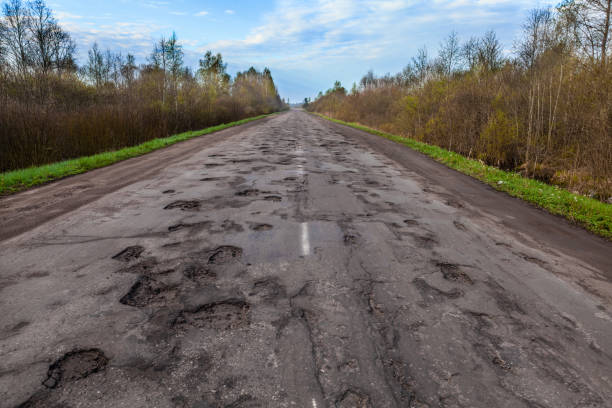 buche pericolose nella strada rurale asfaltata. danni alla strada - road street thoroughfare hole foto e immagini stock