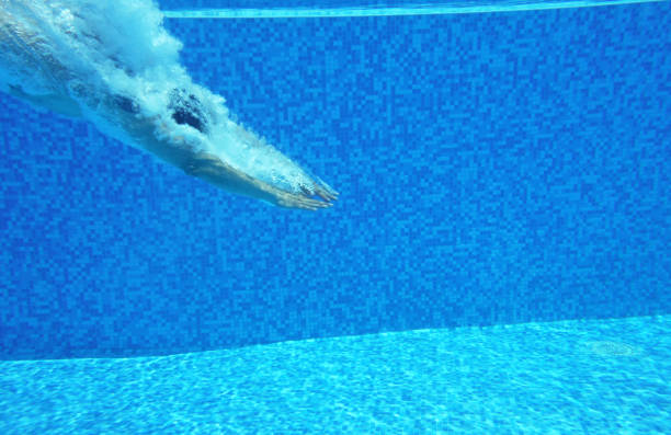 Underwater shot of man diving into pool