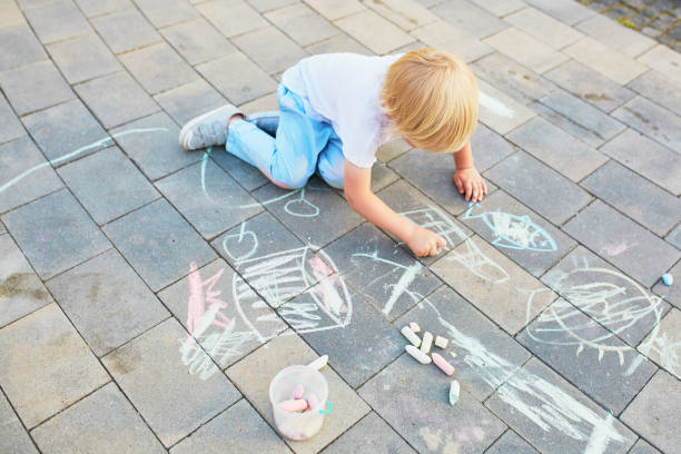 istock Little boy drawing with chalks on asphalt 972855978