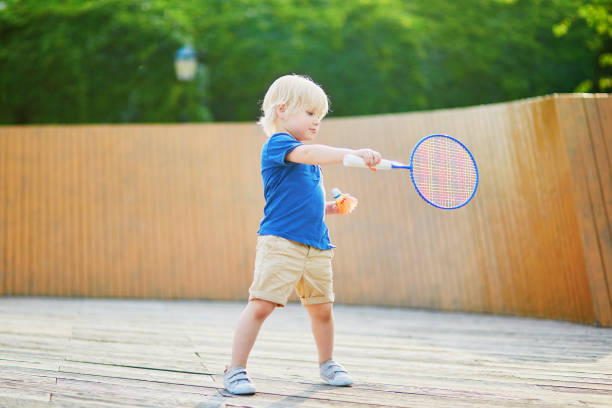 маленький мальчик играет в бадминтон на детской площадке - racquette стоковые фото и изображения
