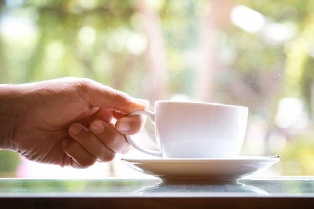 istock A man holding white coffee cup to drink when sitting near window 972865948