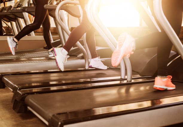 istock Three Young athletic people running on treadmill legs close up. 972869850