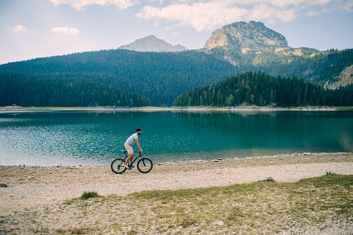 Handsome man cycling by the lake