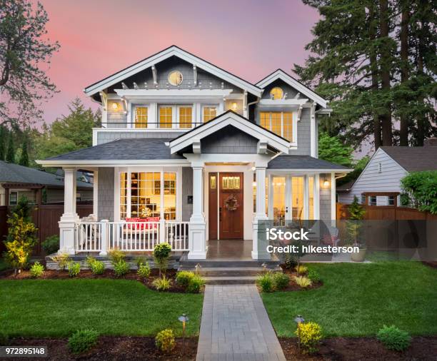Beautiful Luxury Home Exterior With Glowing Interior Lights At Sunset In Suburban Neighborhood Stock Photo - Download Image Now