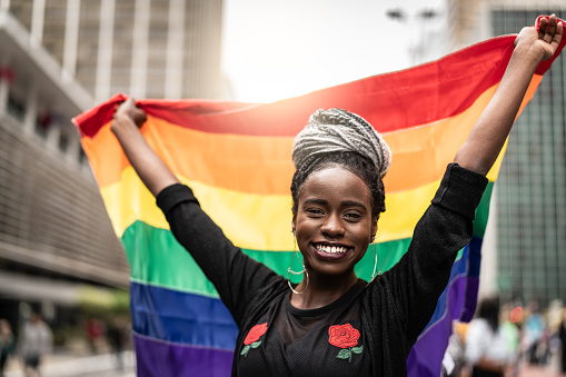Mujer ondeando la bandera del arco iris en el Desfile Gay photo