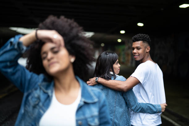 istock Disloyal man with his girlfriend looking at another girl 972902526