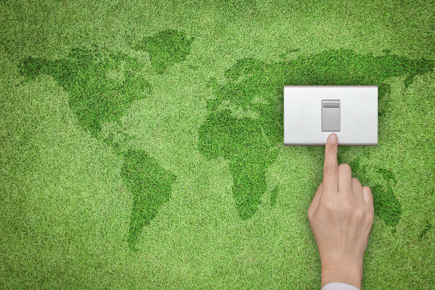 istock Energy saving and ecological friendly concept with hand turning off switch on green grass lawn with world map 972918612