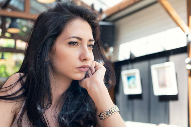 istock Sad girl with phone in cafeteria 972918890