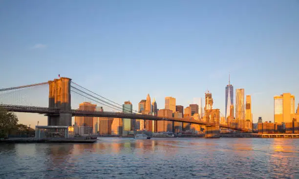 Lower Manhattan skyline and Brooklyn Bridge in New York City at sunrise
