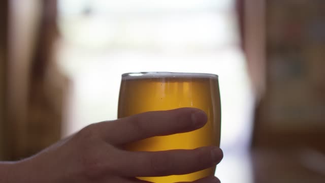 Close-Up Shot of a Bartender Handing a Beer to Someone Else Across a Bar Counter