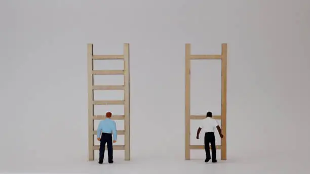 Photo of Racist concepts in employment and promotion. Miniature people and miniature wooden ladders.
