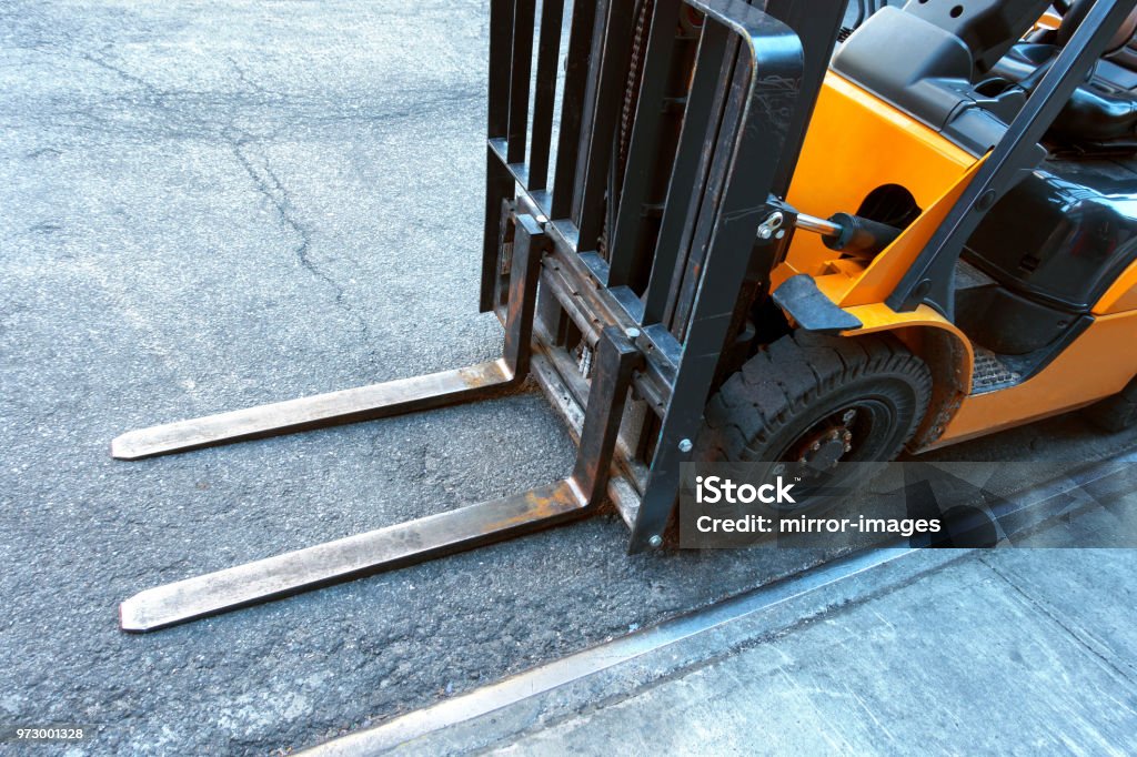 close up of fork lift blades on an urban city street looking down are at the fork lift blades on a tarmac street Forklift Stock Photo