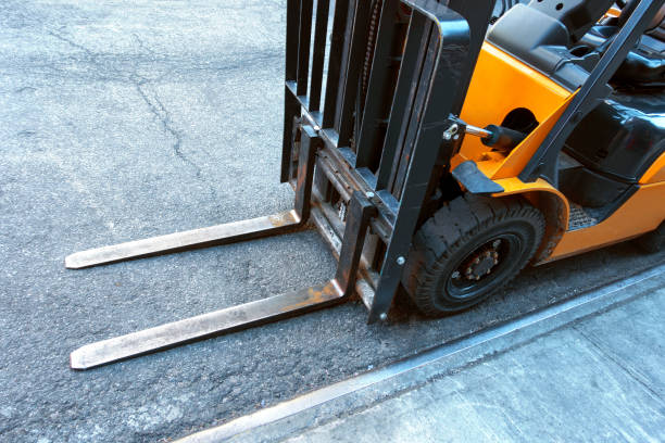 close up of fork lift blades on an urban city street looking down are at the fork lift blades on a tarmac street forklift photos stock pictures, royalty-free photos & images
