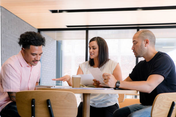 istock Diversity in the workplace - Samoan and Maori/mixed ethnicity employees discussing reports in a business meeting 973006306