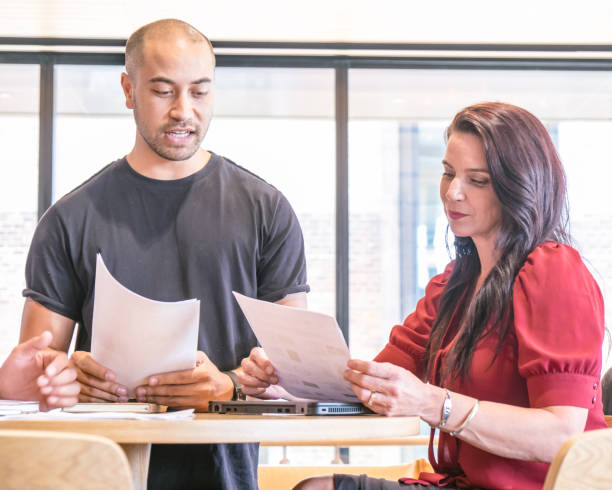 istock Two managers or co-workers having serious discussion reviewing report documents in a business meeting. Diversity in work place with Maori male and caucasian female 973017084