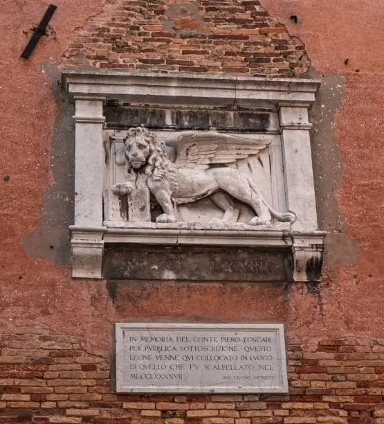 Photo of Stone bas-relief of the Venetian lion on the wall of the Arsenal of Venice. The lion of St. Mark is a symbol of the city of Venice, and one of the elements of the flag of the Italian fleet.