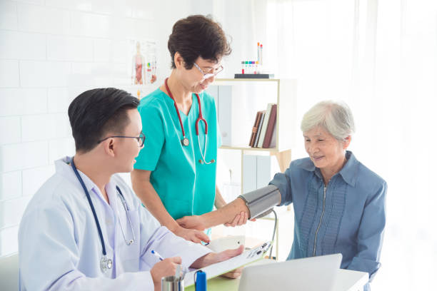 doctor and nurse checking senior woman blood pressure stock photo