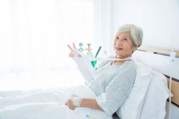Senior patient smiling at camera and showing her broken arm stock photo