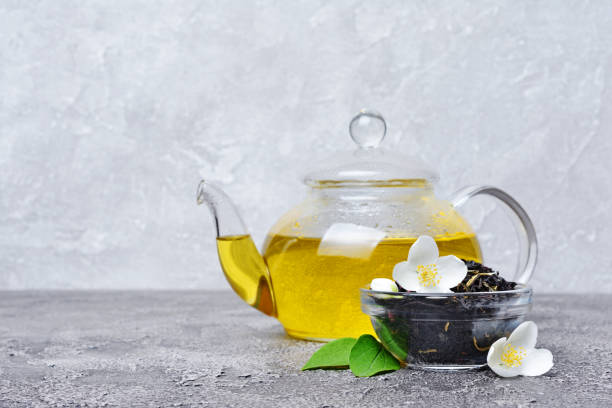 théière en verre gros plan avec des fleurs de jasmin et de thé vert ou noir - jasmine tea black tea tea drink photos et images de collection