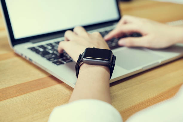 istock woman using laptop  and put a smart watch, film effect. Concept technology and modernization. 973060640