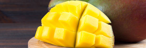 istock Tropical fruit mango on a wooden background, whole or sliced. 973063934
