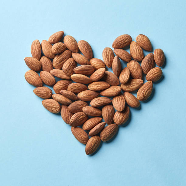 블루 종이 배경에 아몬드에서 심 혼의 형태로 패턴 - people snack almond brown 뉴스 사진 이미지