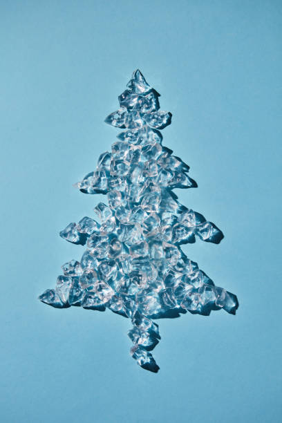 istock Cold ice cubes in the shape of a Christmas tree on a blue background. Flat lay 973070458
