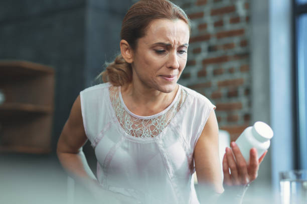 istock Concentrated mature woman examining medication 973092224