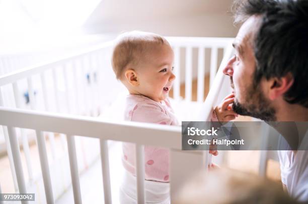 A Small Toddler Girl Standing In Cot With Her Father At Home Stock Photo - Download Image Now