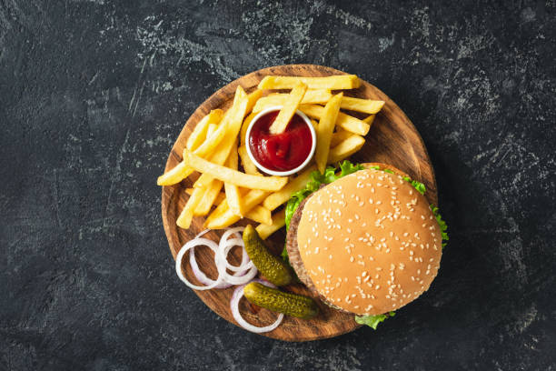 Burger, hamburger or cheeseburger served with french fries, pickles and onion Burger, hamburger or cheeseburger served with french fries, pickles and onion on wooden board. Top view. Fast food concept fast-food-table-top-view stock pictures, royalty-free photos & images