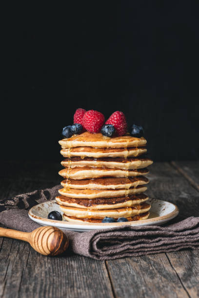 stapel von pfannkuchen mit honig und frischen beeren auf holztisch - pancake stack stock-fotos und bilder