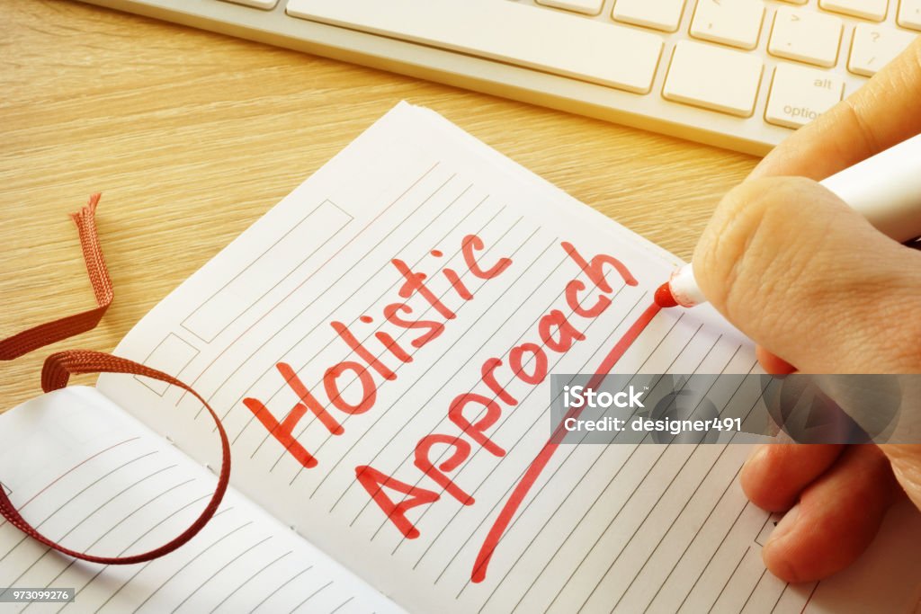 Hand is writing Holistic approach in the note. Alternative Medicine Stock Photo