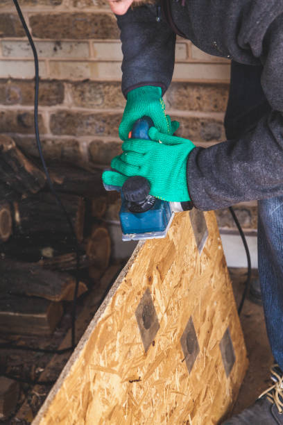 istock hands in gloves plan the wood plate with an electric plane 973100378