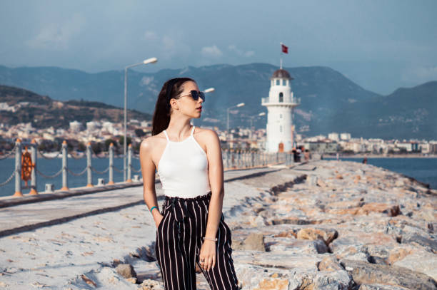istock Pretty thin beautiful girl with a sea view and a lighthouse on background 973104014