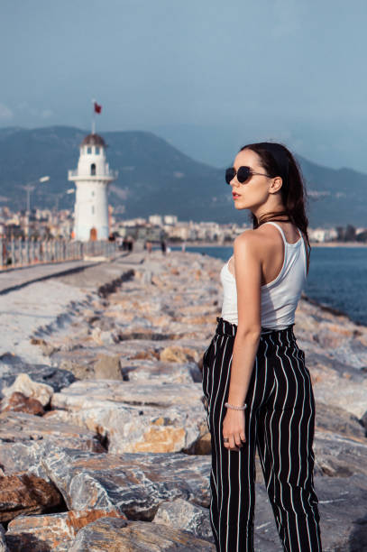istock Pretty thin beautiful girl with a sea view and a lighthouse on background 973106172