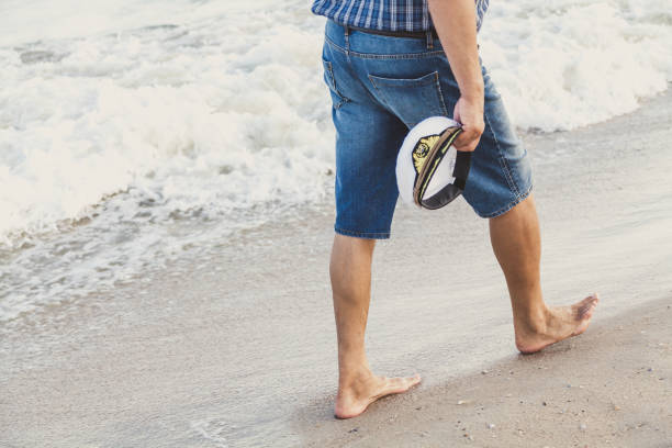 człowiek chodzi po plaży morskiej - cap embroidery blue hat zdjęcia i obrazy z banku zdjęć