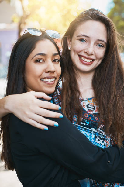 istock Two smiling young women give each other a friendly hug 973117686