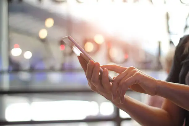 Photo of Close up of women's hands holding smartphone. Her watching sms, message, e-mail on mobile phone in coffee shop. Blurred background.
