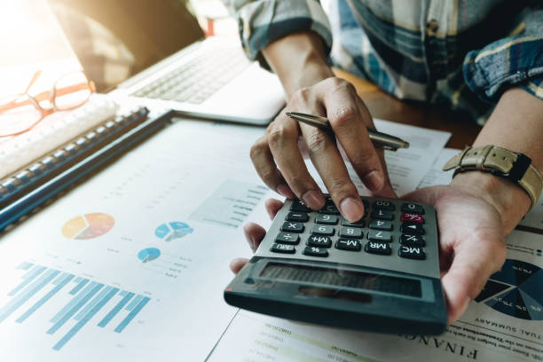 istock A man working about financial and analysis business document with calculator and holding glasses at his office to calculating expenses, Accounting concept 973149642