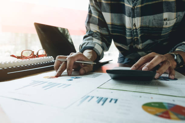 istock A man working about financial and analysis business document with calculator and holding glasses at his office to calculating expenses, Accounting concept 973149654
