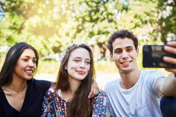 istock Three young people take smiling selfie in park 973154196