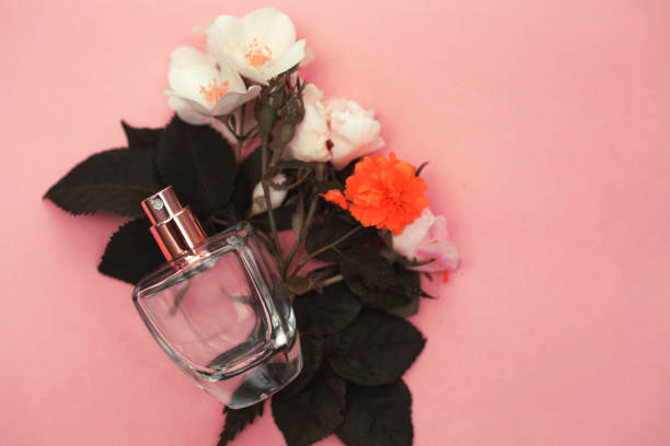 istock Female perfume with flowers on pink background 973162612