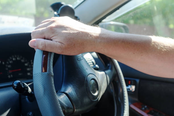 istock men's hands on the steering wheel of the car, inside 973163330