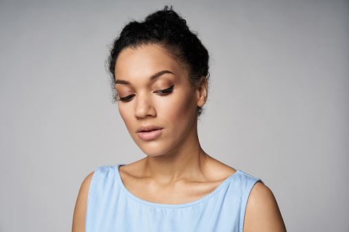 Closeup portrait of beautiful serene mixed race caucasian - african american woman looking down, isolated on gray background