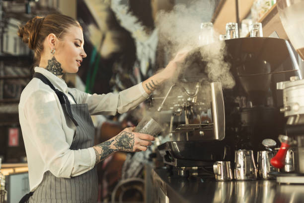 istock Tattooed barista making coffee in professional coffee machine 973172970