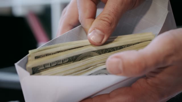 Close up of cash money in envelope in hands. Money bonus in paper envelope