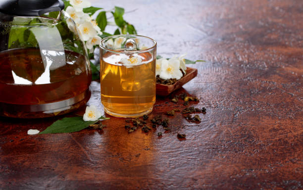 istock Green tea with jasmine in cup and teapot on old copper table. 973177128